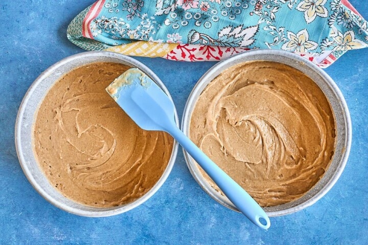 batter distributed into 2 round pans with a spatula and a dish towel
