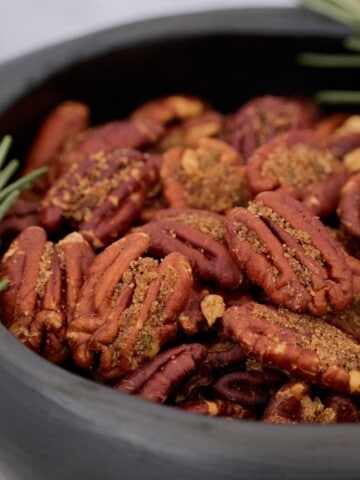 a close-up photo of finished pecans with rosemary sprigs