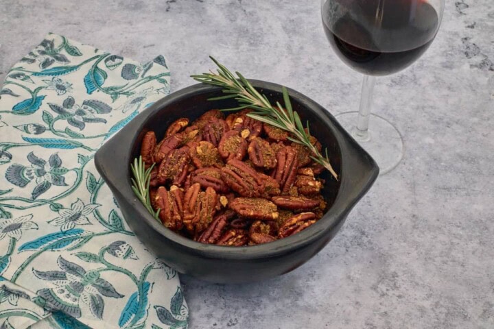 nuts in a bowl with a napkin and glass of wine