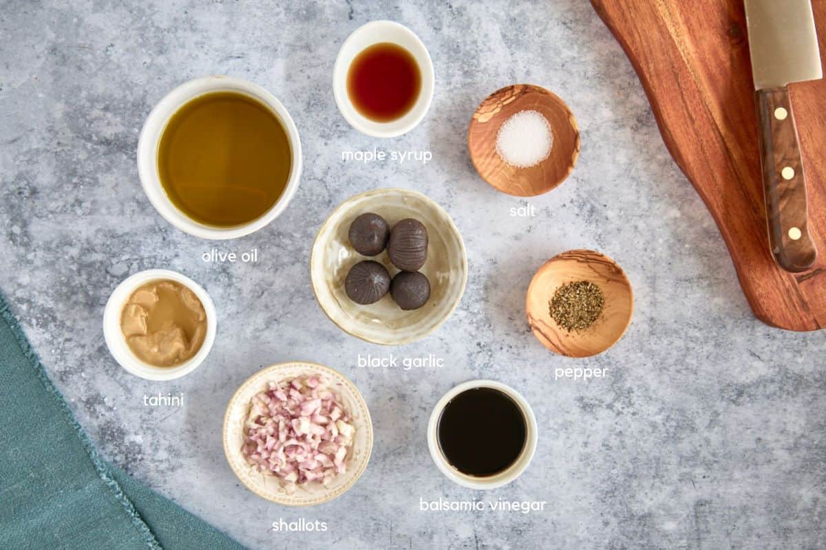 labeled salad dressing ingredients in separate bowls with a cutting board, knife, and napkin alongside