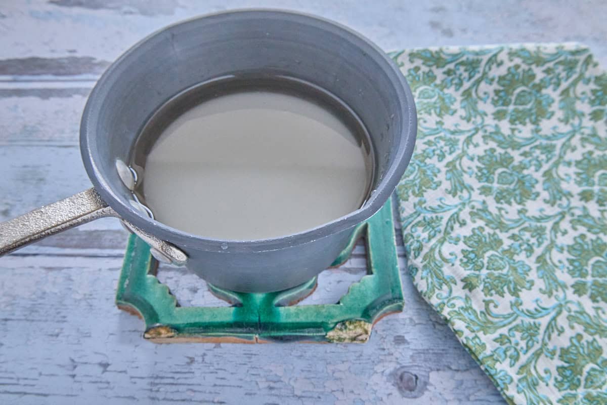 a small pan of sugar and water on a trivet with a napkin alongside