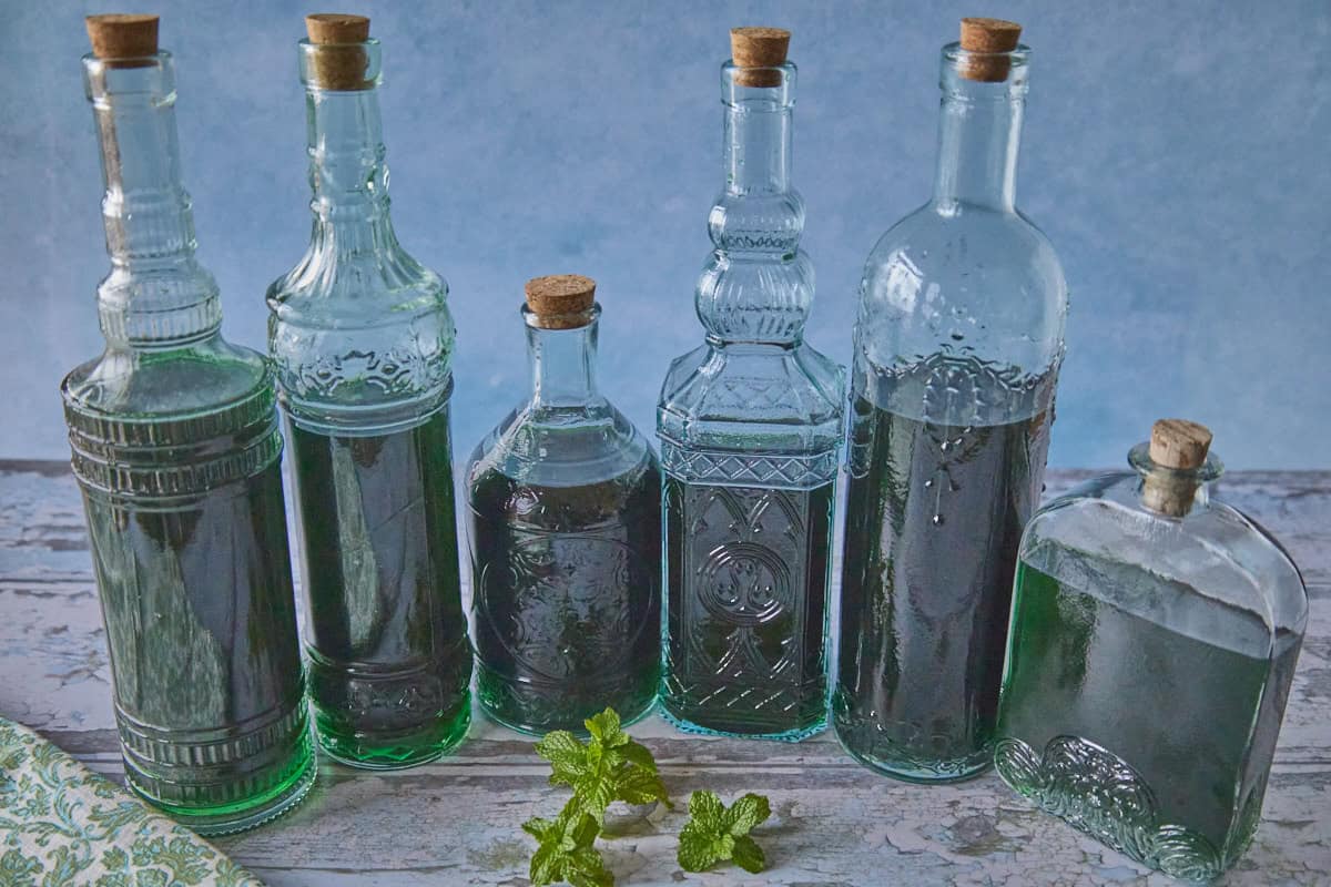 6 bottles of liqueur with a napkin and some fresh sprigs of mint in the foreground