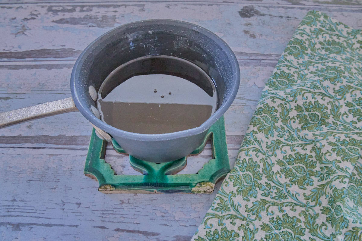 a small pan of simple syrup on a trivet with a napkin alongside