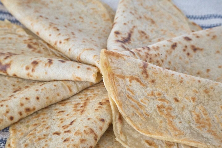 some tortillas folded in half and arranged like a pinwheel atop a kitchen towel