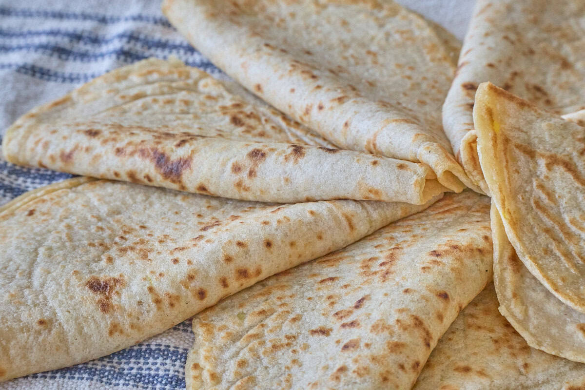 an offset photo of some tortillas folded in half and arranged like a pinwheel atop a kitchen towel