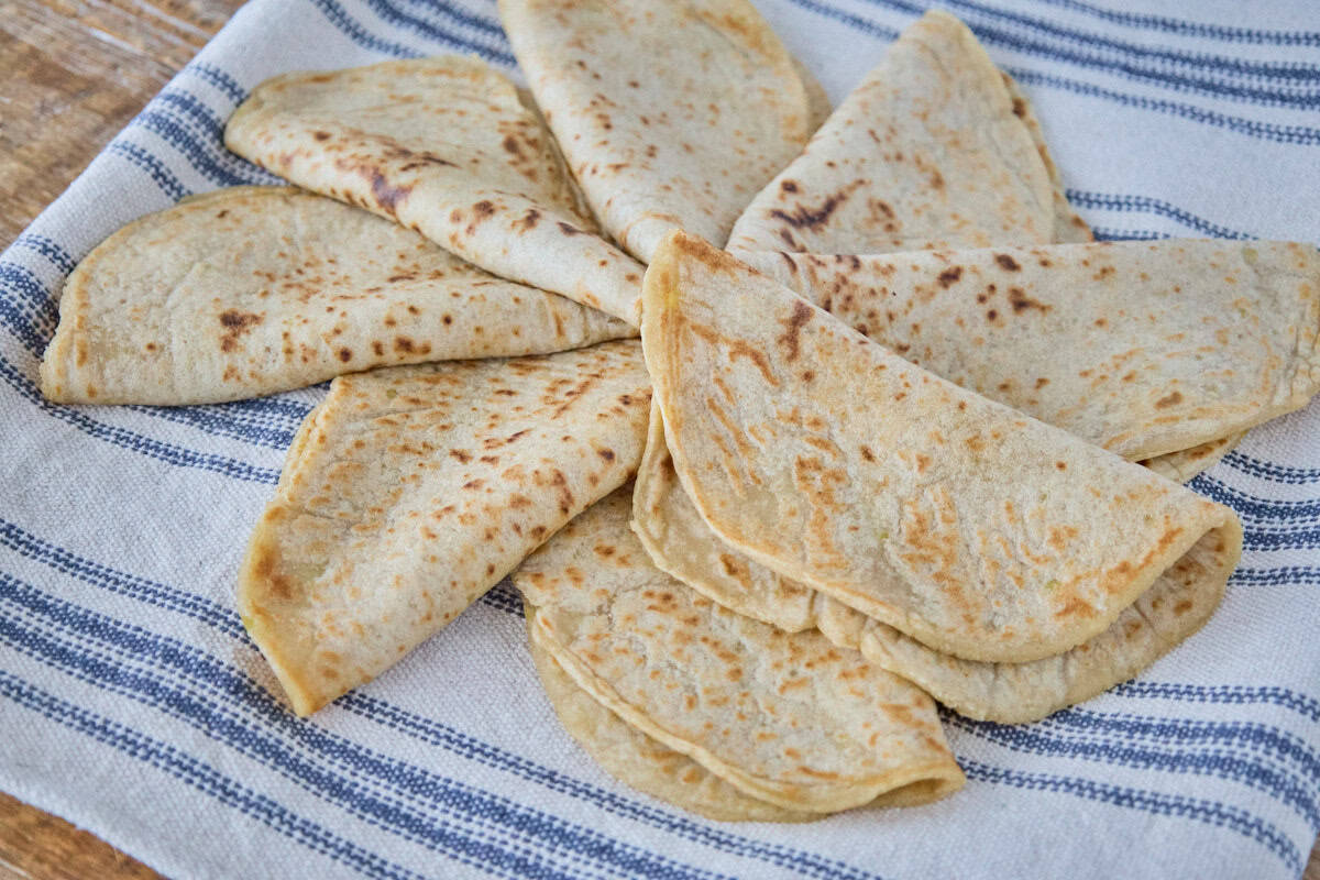 a mid-range shot of some tortillas folded in half and arranged like a pinwheel atop a kitchen towel