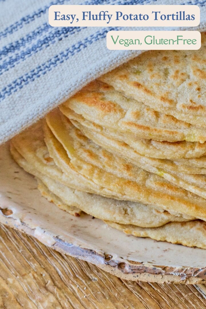 a plate of tortillas on a rustic table with a kitchen towel draped over the top