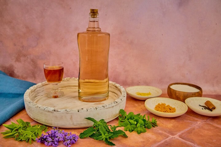 fresh herbs, alcohol on a tray, citrus zest, sugar, and spices for version 5 of the vin d'orange, with a napkin in the background