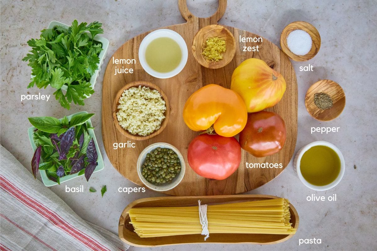 labeled ingredients on a wooden board in bowls and alongside, with a kitchen towel in the foreground