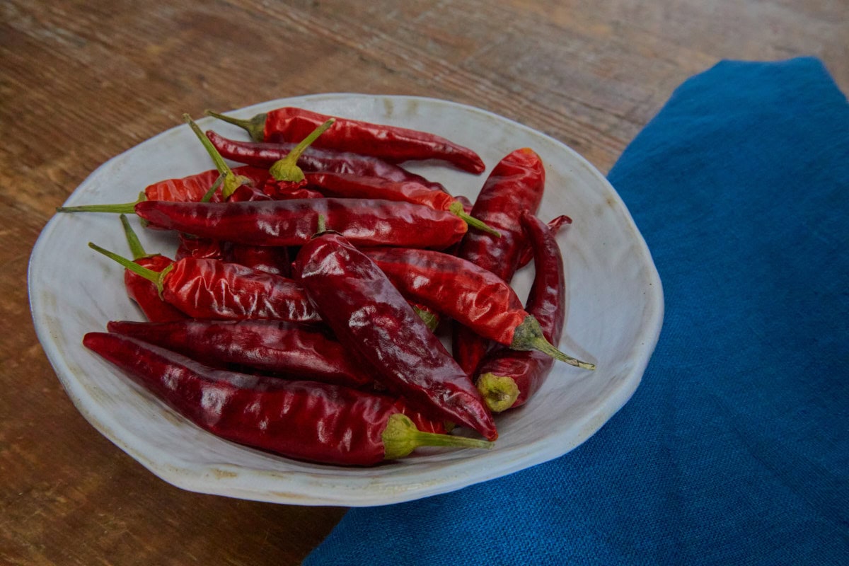 dried birdseye peppers in a dish with a napkin alongside