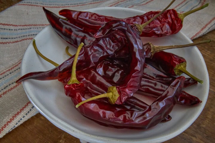 dried guajillo peppers in a dish with a kitchen towel in the background
