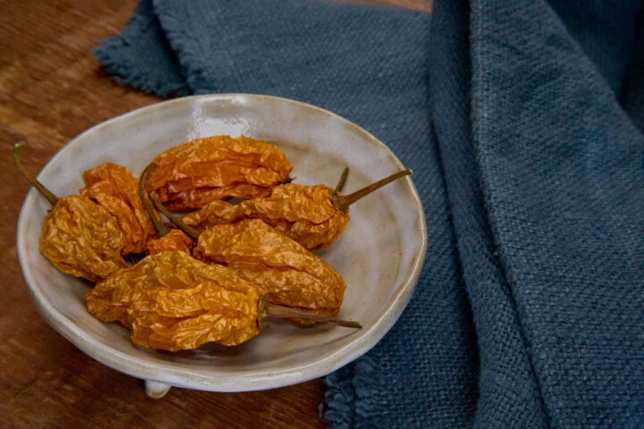 dried scotch bonnet peppers in a bowl with a napkin alongside