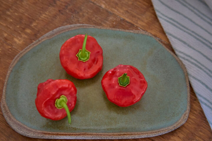 fresh aji dulce peppers on a plate with a kitchen towel alongside