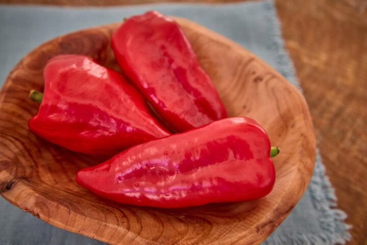 fresh beaver dam peppers in a wooden bowl atop a napkin
