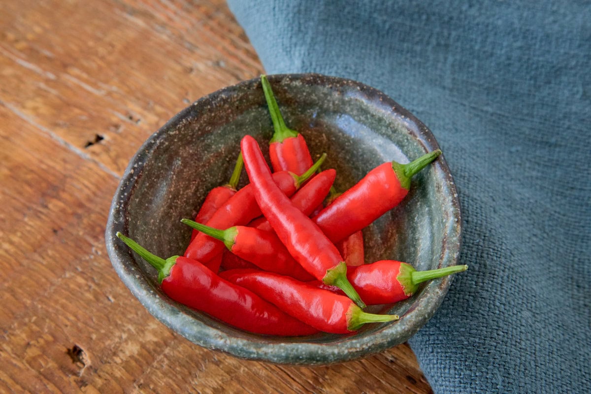 fresh birdseye peppers in a bowl with a napkin in the background