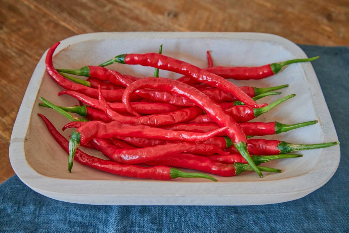 fresh cayenne peppers in a wooden bowl atop a napkin