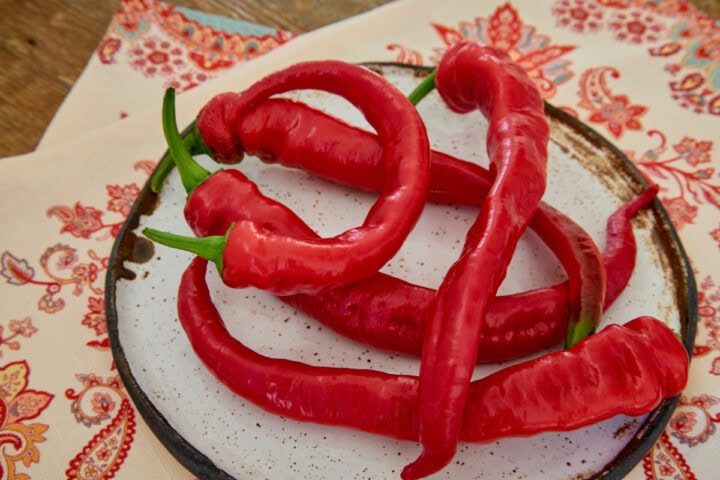 fresh jimmy nardello peppers on a plate atop a kitchen towel