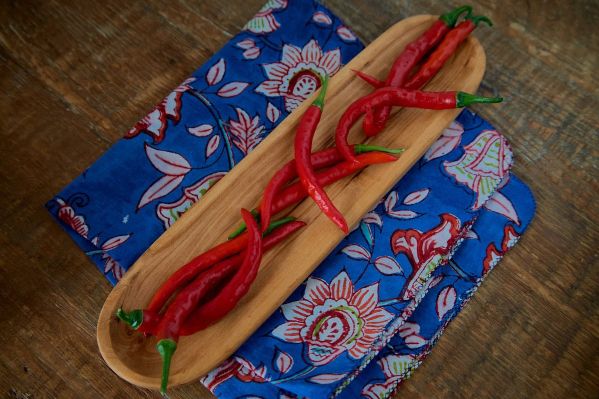 fresh kashmiri peppers in a wooden bowl atop a napkin