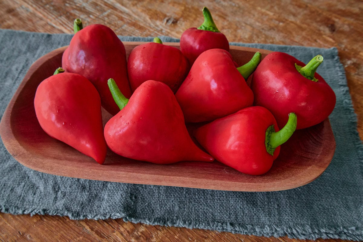 fresh lesya peppers in a wooden bowl atop a napkin