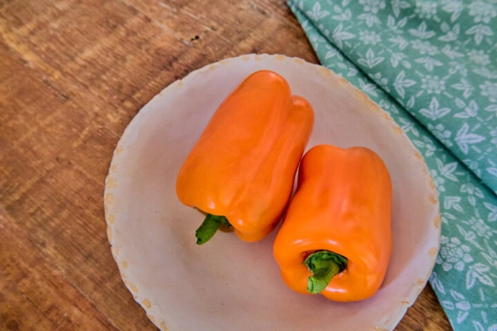 fresh orange marmalade peppers in a bowl with a kitchen towel in the background