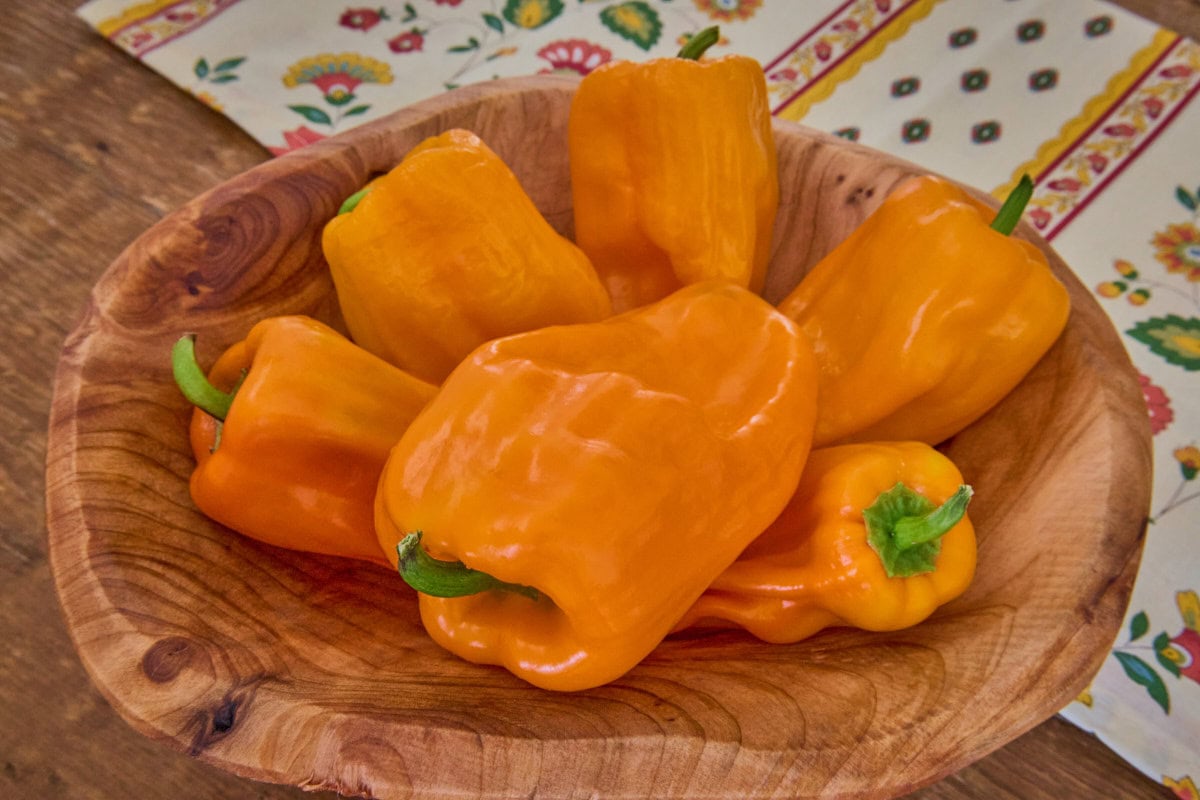 fresh petit marseillais peppers in a wooden bowl with a napkin in the background