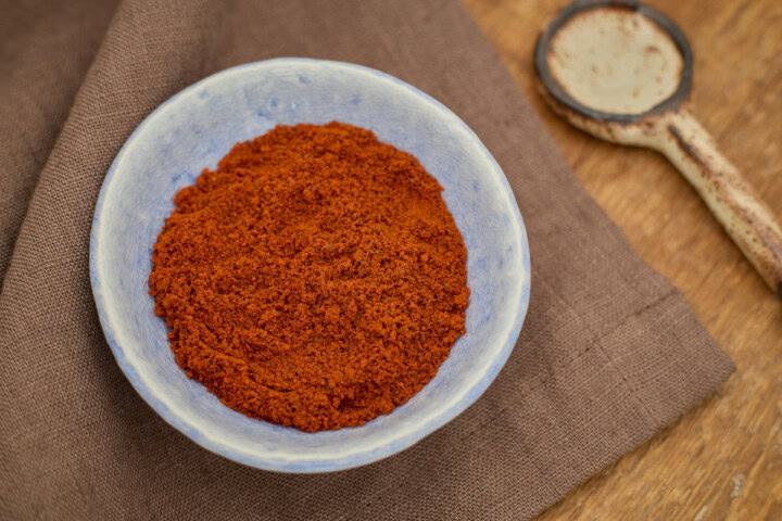 catarina pepper powder in a small bowl atop a napkin with a ceramic spoon in the background