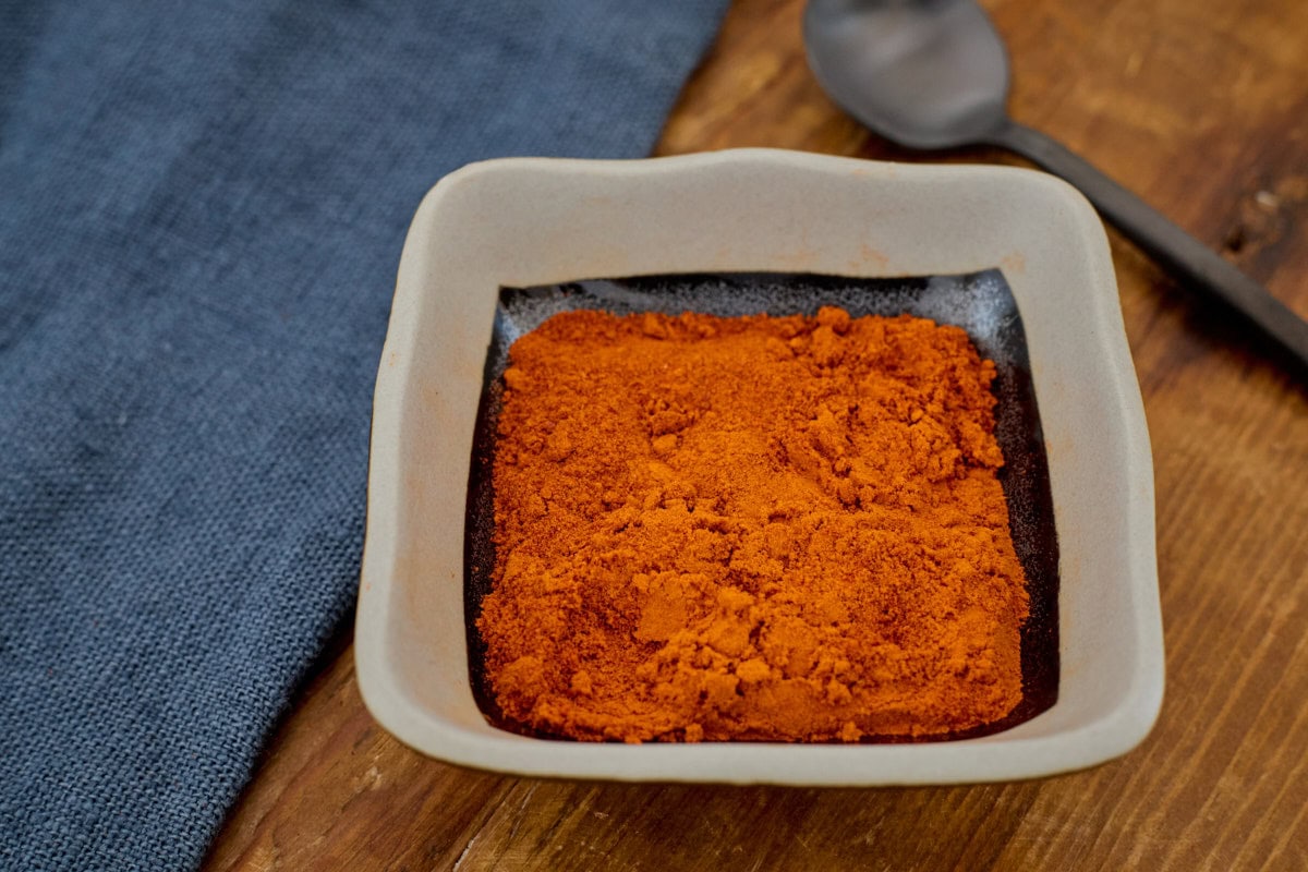 padron pepper powder in a small square bowl with a spoon and a napkin in the background