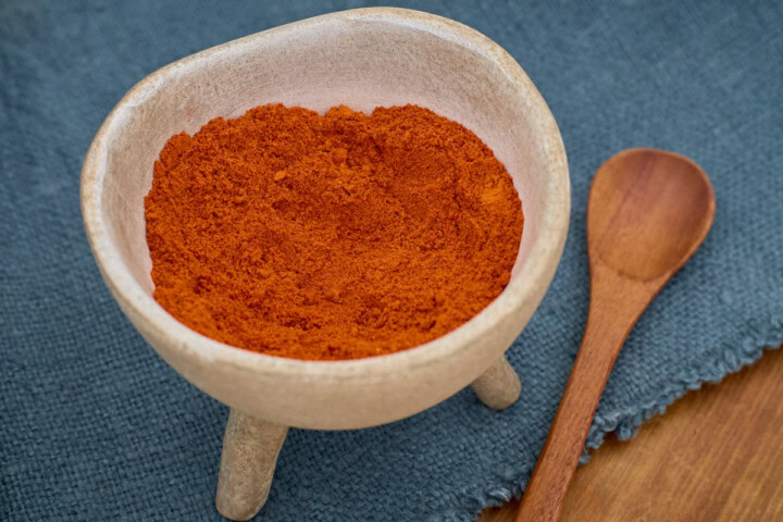 pasilla bajio chilaca pepper powder atop a napkin with a wooden spoon alongside
