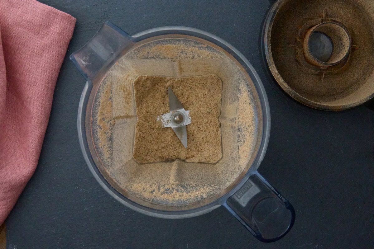 ground dried rice in a blender with a napkin and the blender top alongside