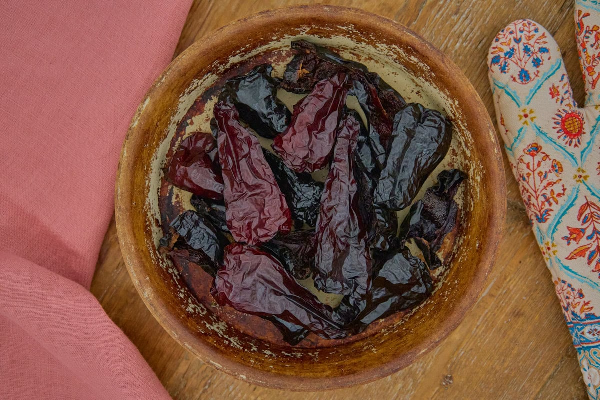 a bowl of dried, smoked leutschauer paprika peppers with a napkin and an oven mitt alongside