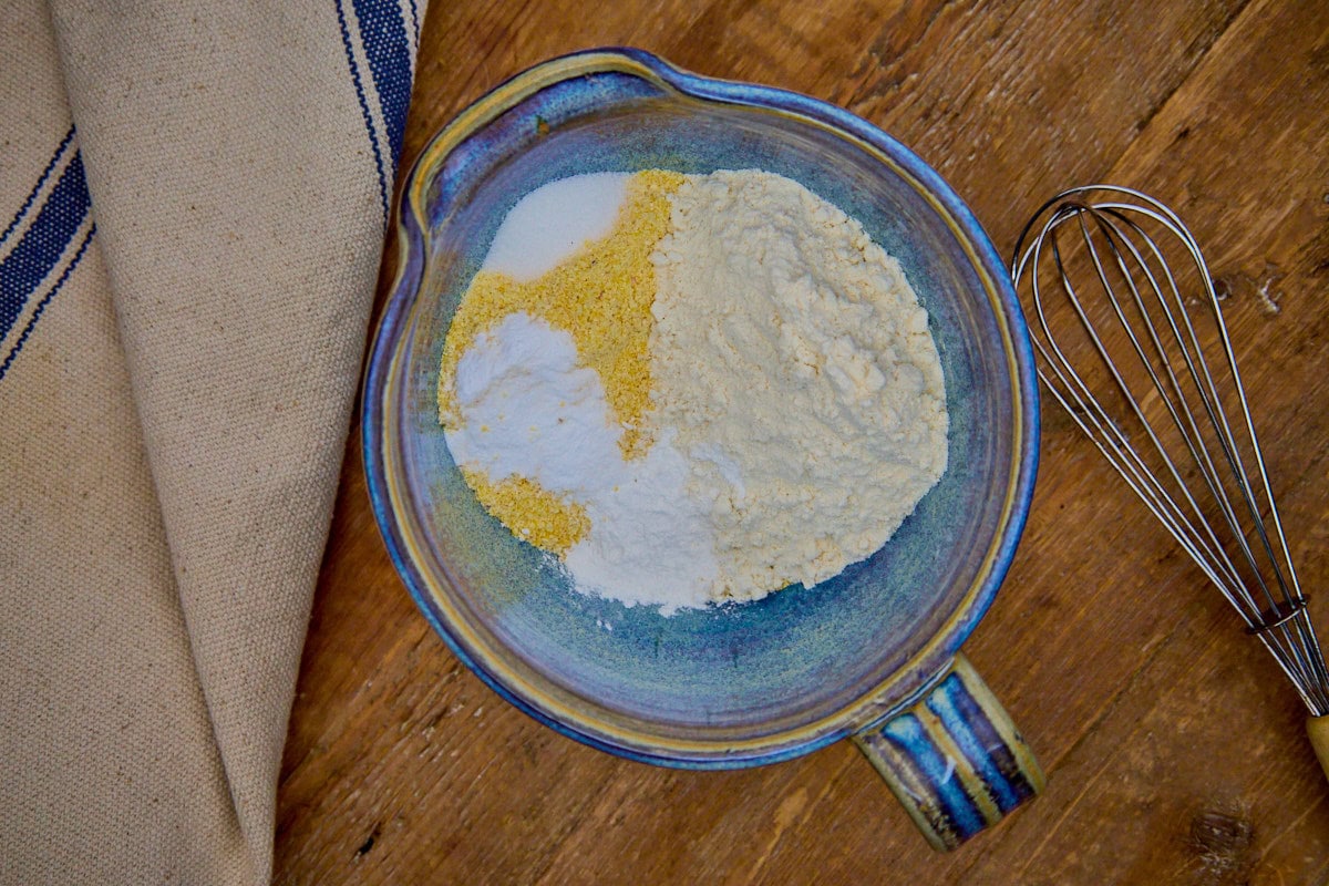 dry ingredients in a mixing bowl with a whisk and kitchen towel in the background