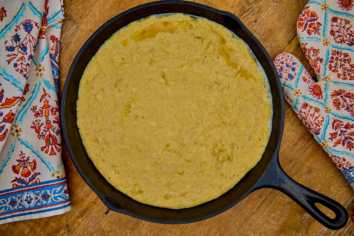 batter in a skillet with a kitchen towel and oven mitt alongside
