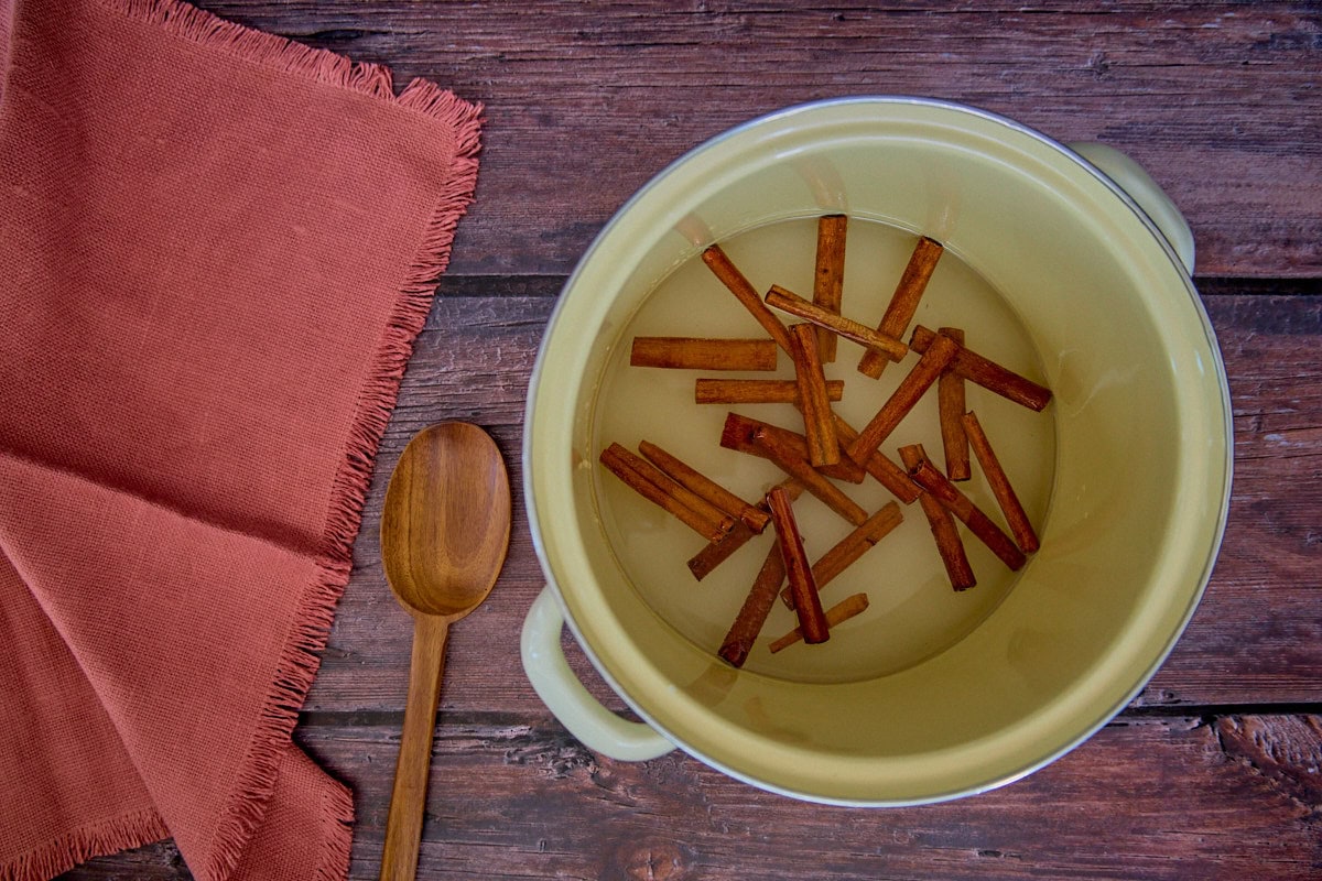 cinnamon syrup ingredients in a pot along with a wooden spoon and napkin