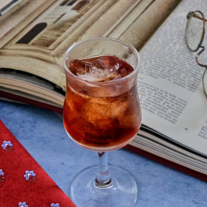 A glass of liqueur and glasses on a table next to an open book