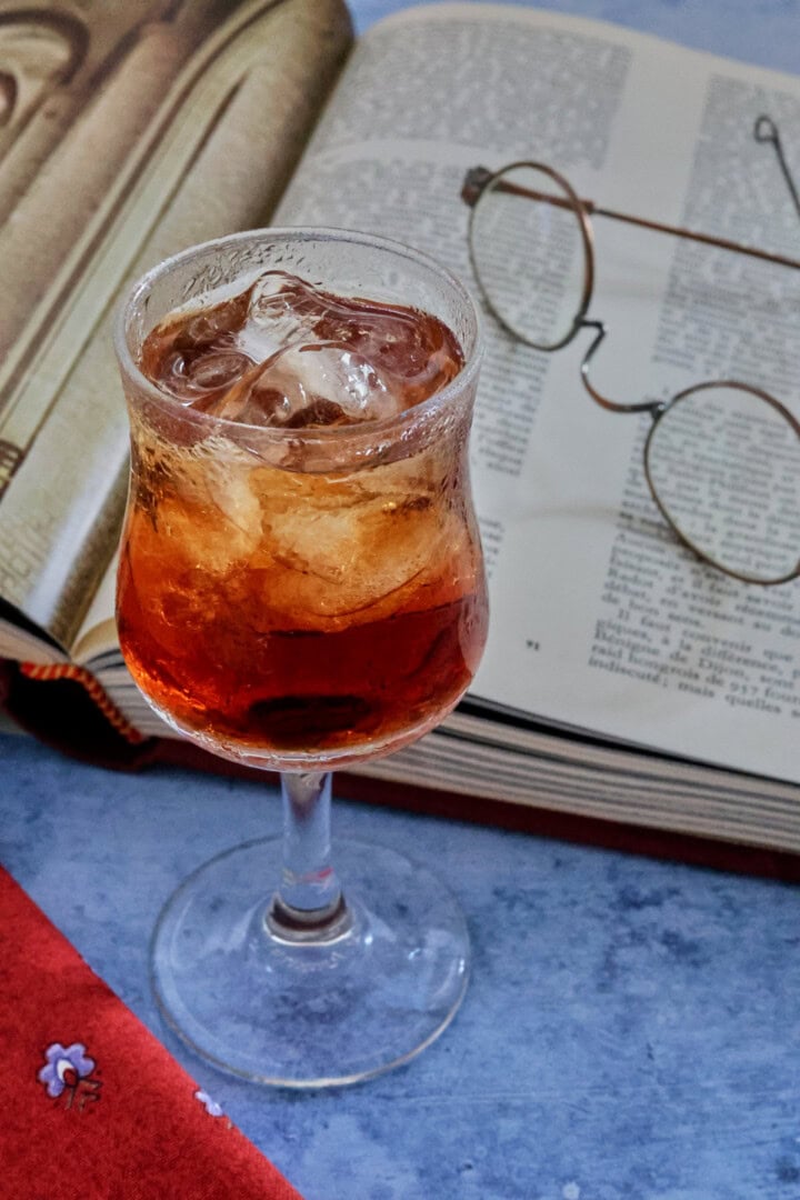 A glass of liqueur with glasses and a book
