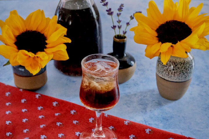 A glass of liqueur with flowers, a napkin, and a bottle of liqueur