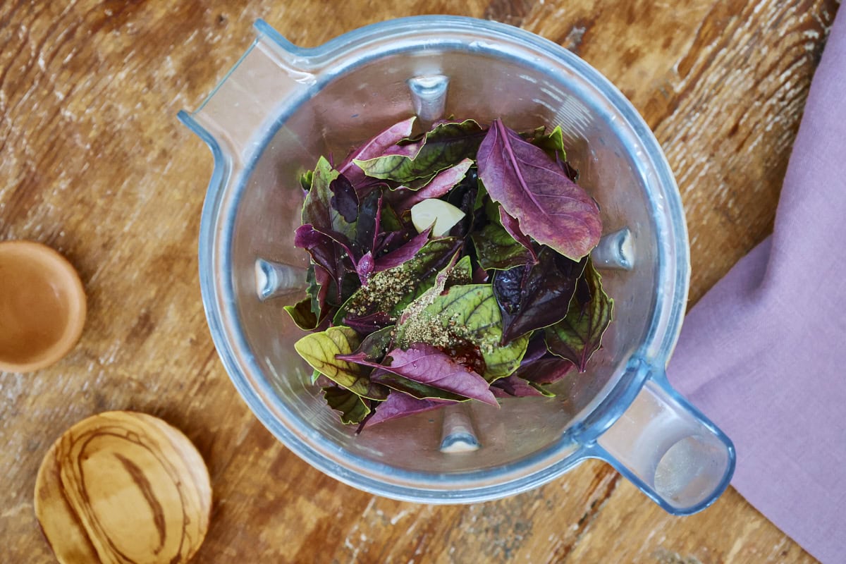 a blender container with ingredients for purple basil vinaigrette, napkin, and 2 small bowls