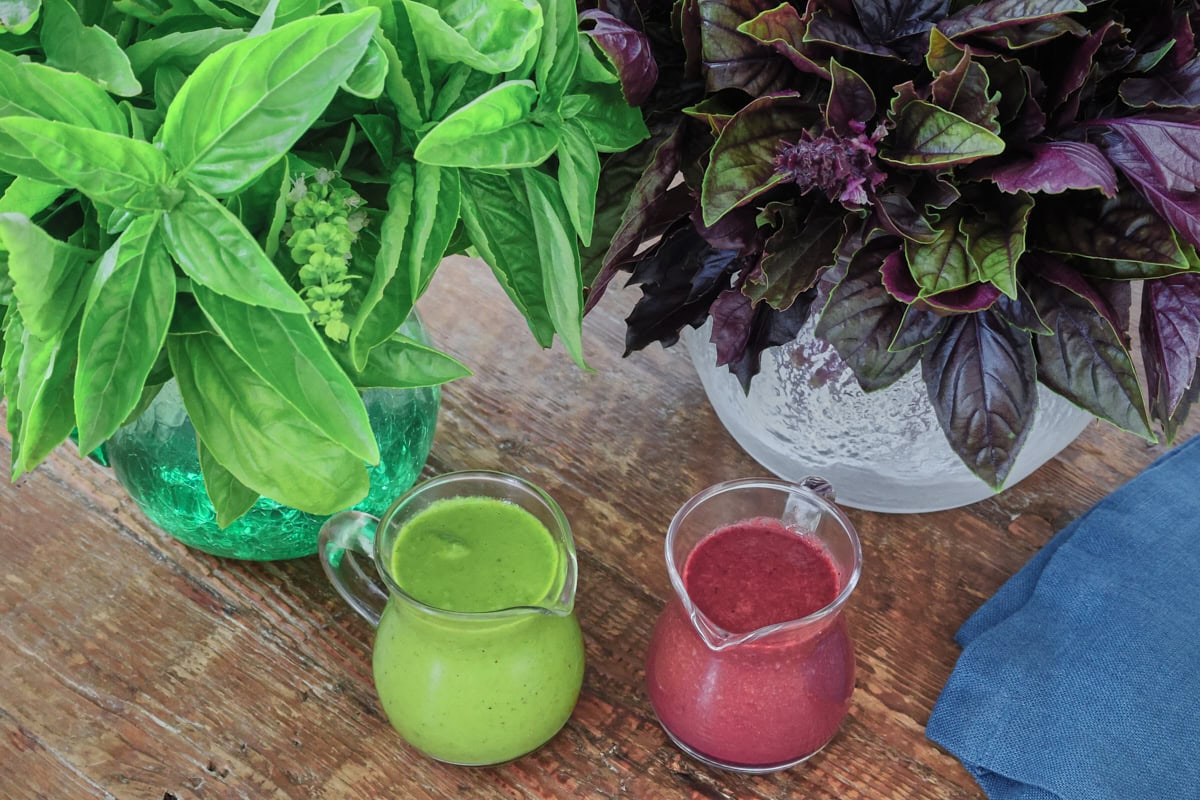 small pitchers of green and purple basil vinaigrette, napkin, and vases of green and purple vinaigrette leaves