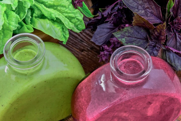 green and purple basil vinaigrette in small bottles and leaves of basil in bowls