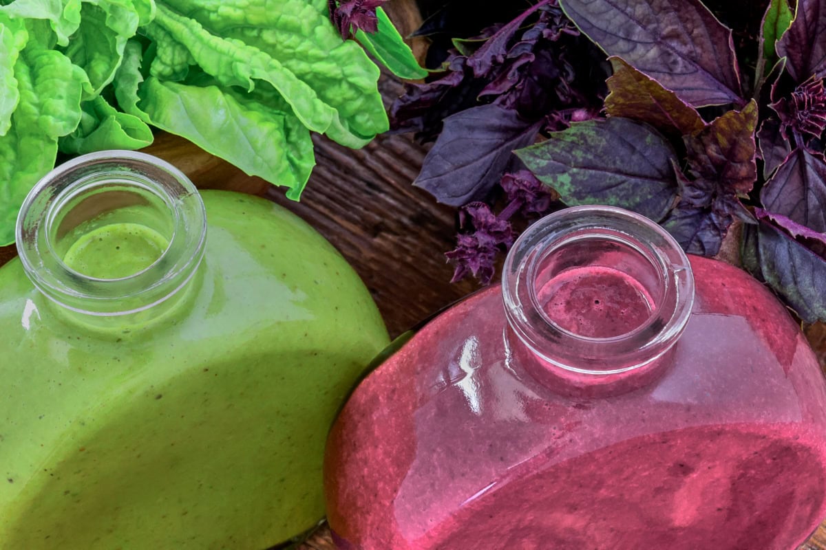 green and purple basil vinaigrette in small bottles and leaves of basil in bowls
