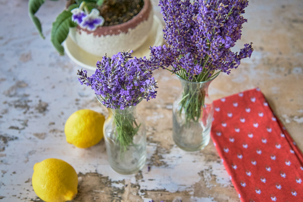 lavender in vases, lemons, a napkin, and a potted flowering plant