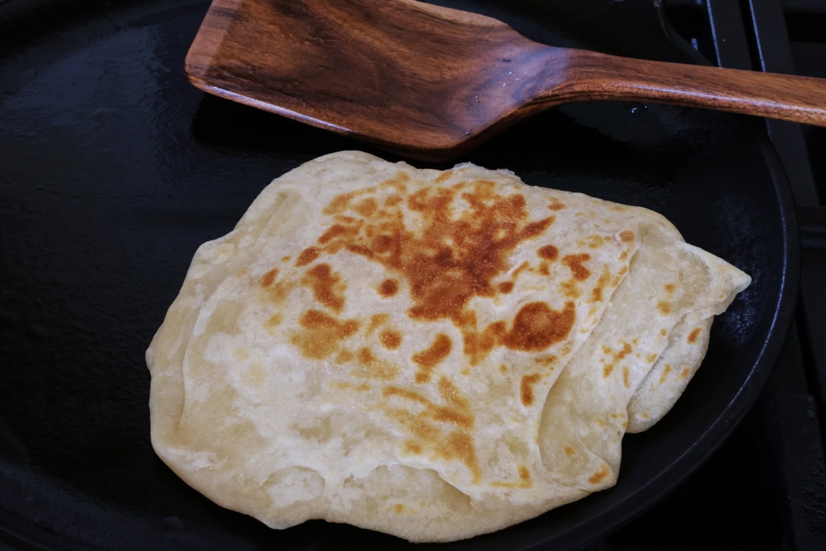 a farata flatbread in a skillet with a wooden spatula