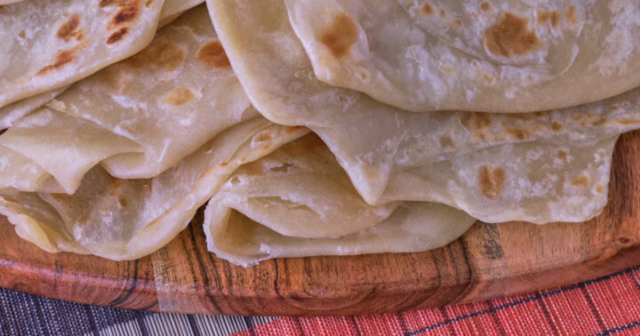 flatbreads on a wood board over a table runner