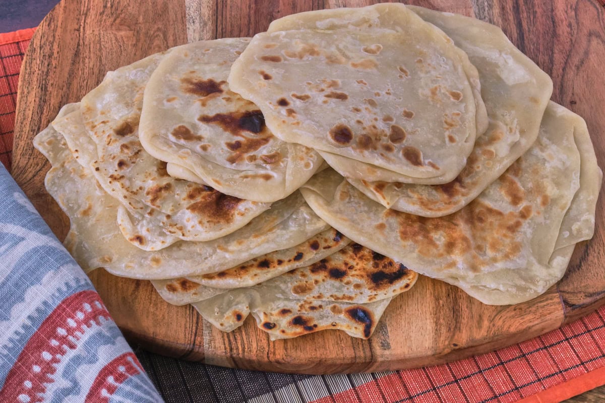 flatbreads on a wood board with a table runner and kitchen towel