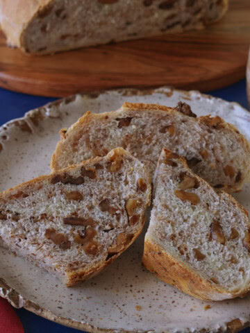 sliced bread on a plate, a napkin, bread on a cutting board, and a cup of coffee