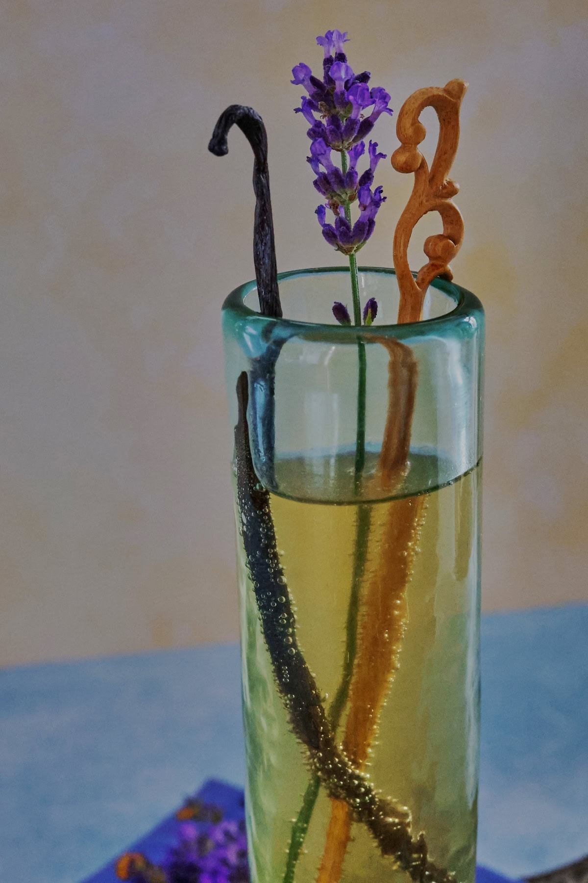 a cocktail in a champagne glass with a napkin, vanilla beans, and fresh lavender sprigs