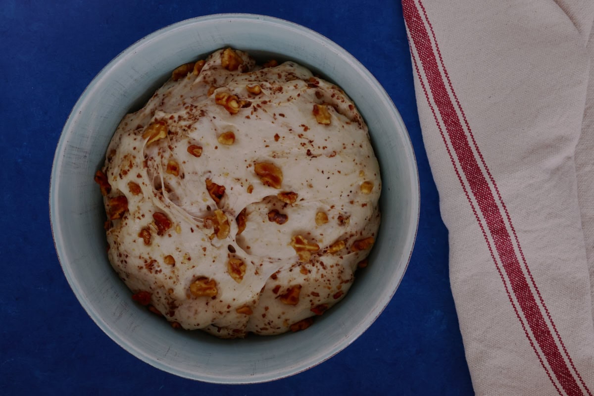 bread dough that has risen in a large bowl with a kitchen towel alongside