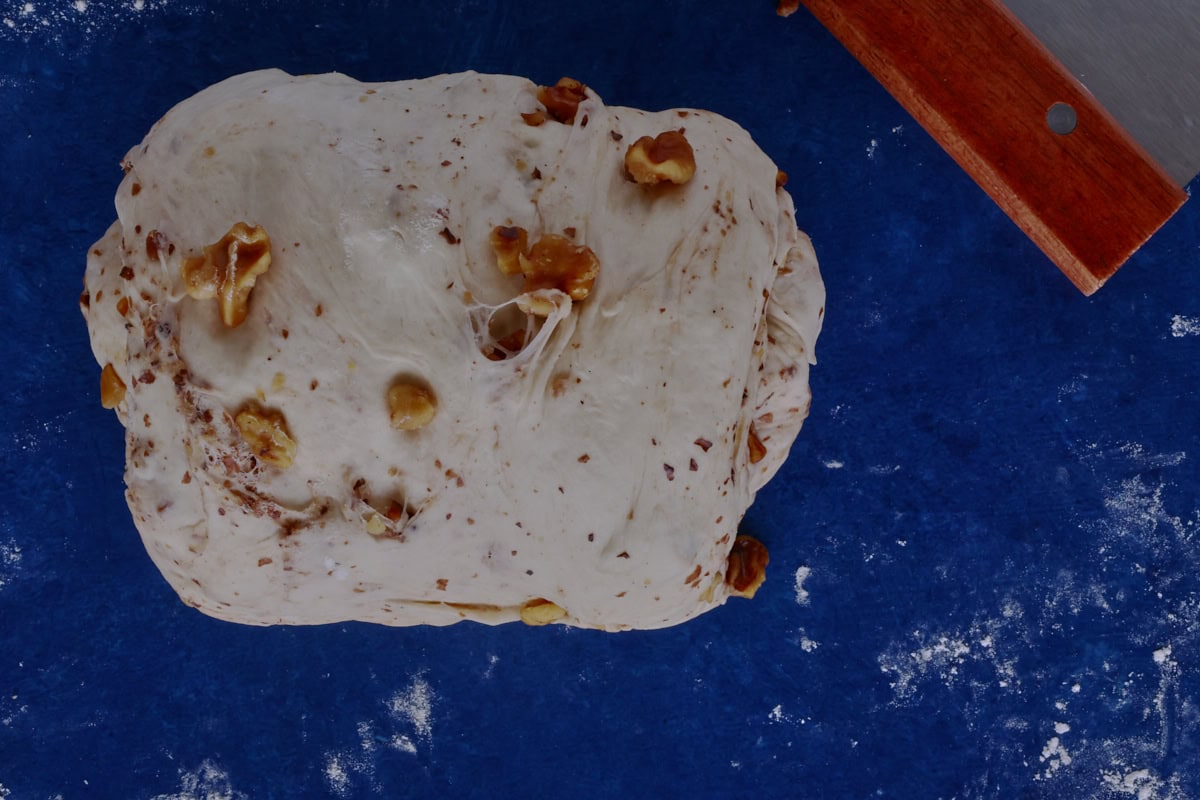 a rolled up batch of bread dough with a bench scraper