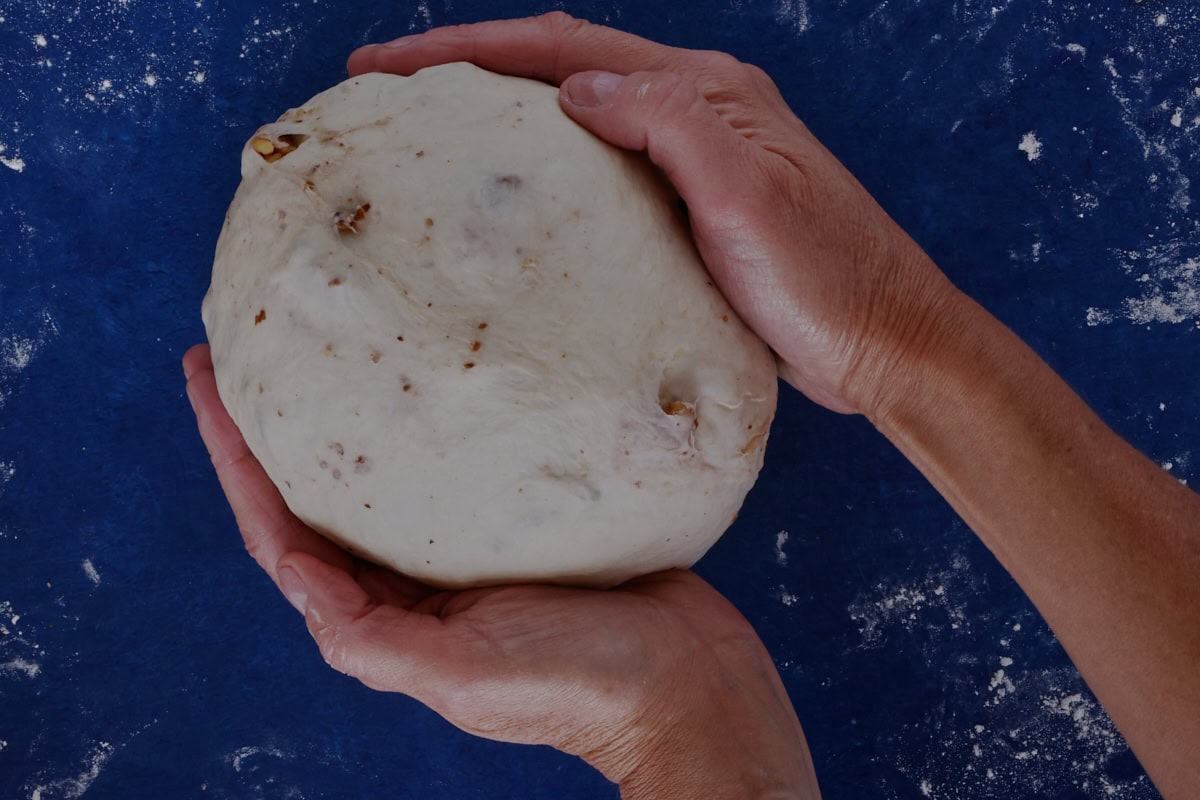 hands shaping a round boule of bread dough