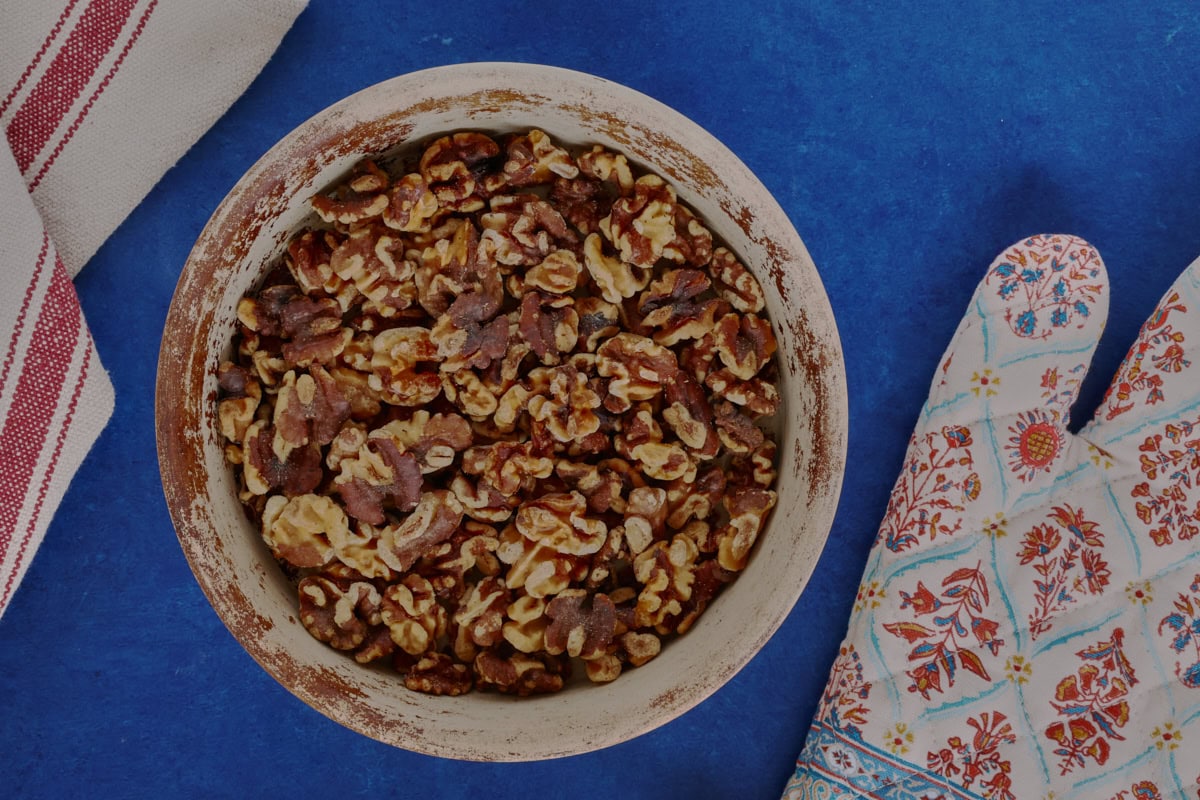 a bowl of toasted walnuts, kitchen towel, and oven mitt